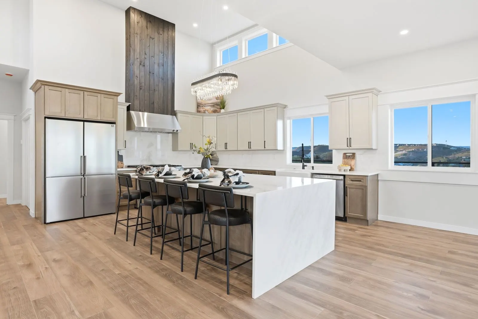 Open kitchen with 10-foot waterfall quartz island, crystal chandelier and 16-foot vaulted ceiling
